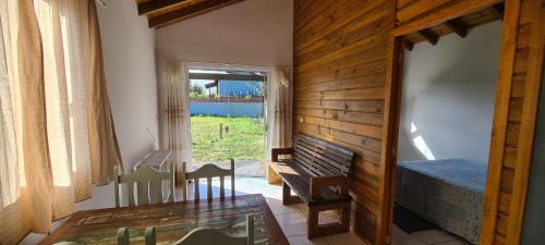 a room with a bench and a table and a window at Moradas do Maneca Chalé da Lagoa in Imbituba