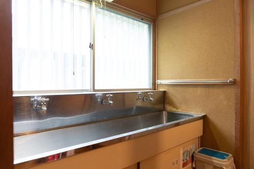 a bathroom with a stainless steel sink and a window at The Sake Kura villa in Hakuba