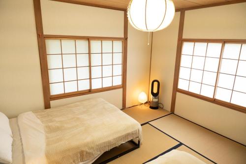 a room with a bed in a room with windows at The Sake Kura villa in Hakuba