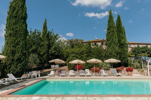 una piscina con sedie e ombrelloni di Villa Di Sotto a Castelnuovo Berardenga