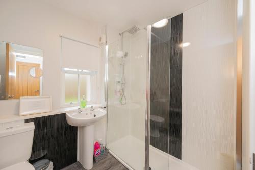 a white bathroom with a shower and a sink at The Lodge House Callander in Callander