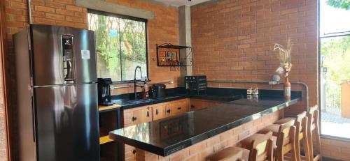 una grande cucina con frigorifero in acciaio inossidabile di Chalé Sol - Vila Doiideira - centro de Ibitipoca a Lima Duarte