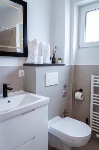 a white bathroom with a toilet and a sink at Moderne Ferienwohnung mit Sonnenterrasse & Gartenblick - Strandnah und hohem Schlafkomfort in Scharbeutz