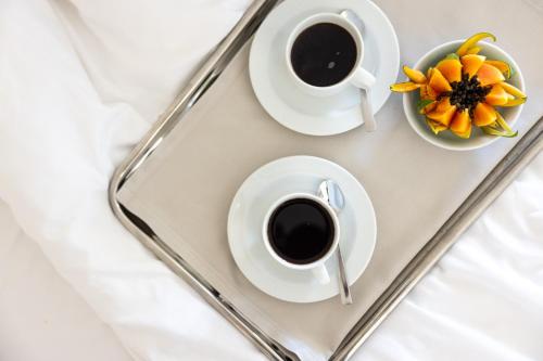 twee kopjes koffie en een schaal met bloemen op een dienblad bij Divani Escape - Adults Only in Athene