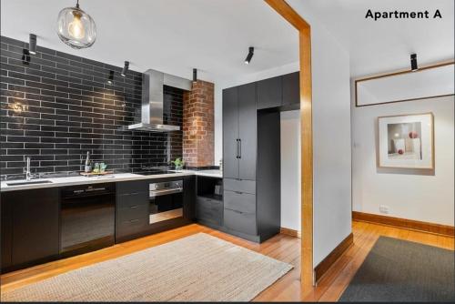a kitchen with black cabinets and a brick wall at Renovated home in central location in Sandy Bay
