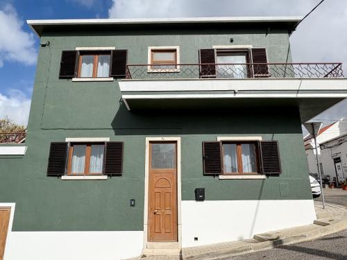 a green house with a door and a balcony at VT Guest House in Setúbal
