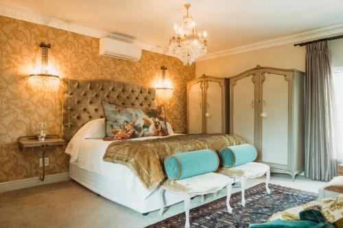a bedroom with a large bed and a chandelier at Baruch Guesthouse on Lovell in Stellenbosch