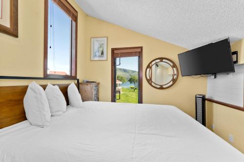ein Schlafzimmer mit einem großen weißen Bett mit einem großen Fenster in der Unterkunft Lake Chelan Shores - Waterfront Dream 11-4 in Lakeside