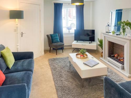 ein Wohnzimmer mit einer blauen Couch und einem Kamin in der Unterkunft Pelican Rest - Uk41429 in Amble