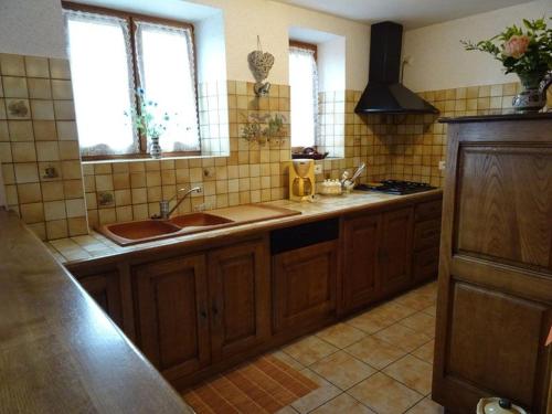 a kitchen with wooden cabinets and a sink and two windows at Gîte à Luc in Mandailles