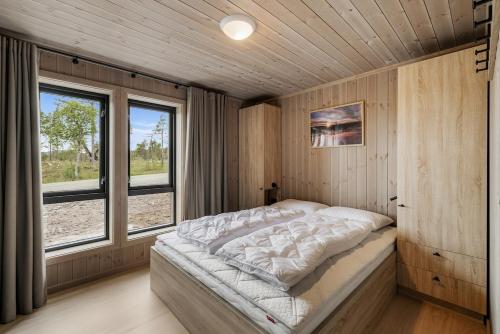 a bedroom with a bed in a room with windows at Sentralt plassert hytte, alt i gangavstand in Flå