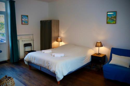 a bedroom with a bed and a blue chair at Chambre d'hôtes rénovée du XVIII ème in Saint-Aubin-la-Plaine