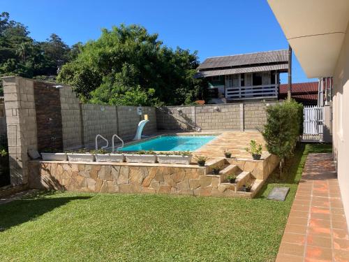 ein Hinterhof mit Swimmingpool und Stützmauer in der Unterkunft Casa 183 in Itajaí