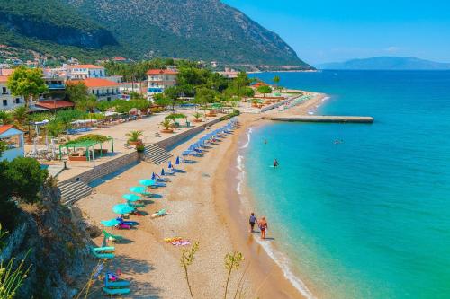 a beach with umbrellas and people on the beach at Anemos Studios & Apartments in Póros Kefalonias