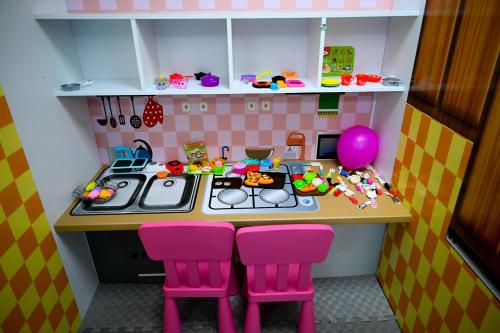 a doll house kitchen with pink stools and a table at Aqua Raj ND in Novi Pazar