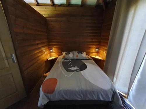 a small bed in a wooden room with two lights at Studio cosy à La Plaine-des-Palmistes, 18 m², jardin in Bras des Calumets