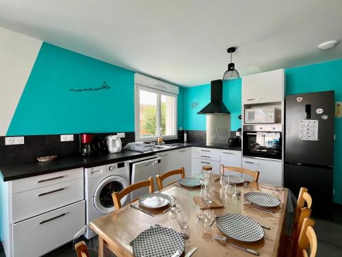 Una cocina con una mesa con sillas y una pared azul. en Ti'Belot - calme près de la mer, en LʼAiguillon-sur-Mer