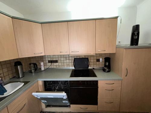 a kitchen with wooden cabinets and a black dishwasher at detached bungalow, 5 beds wifi smart tv terras 3 parkings keybox in Emlichheim