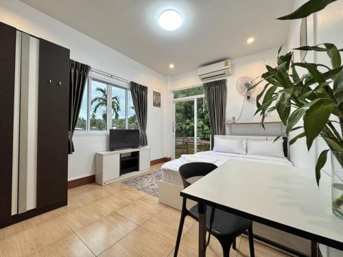 a bedroom with a bed and a table and a tv at PROpaganda Guest House in Thongsala