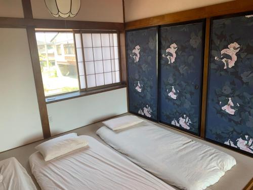 a room with two beds and two windows at 鶴岡市中心地ゲストハウス in Tsuruoka