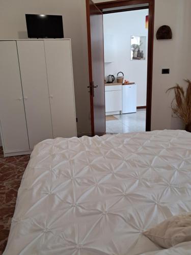 Un dormitorio con una gran cama blanca y una cocina. en Prisciò, en Melendugno