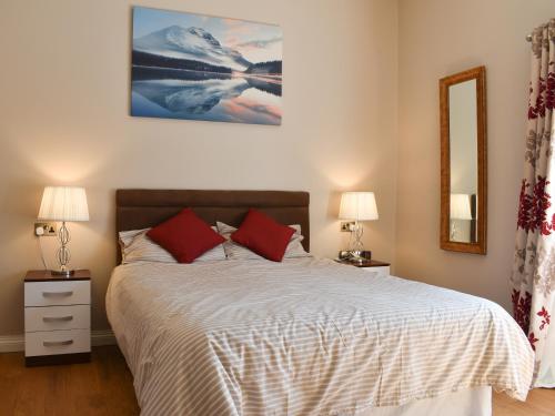 a bedroom with a bed with two lamps and a mirror at Beckside House in Dalton in Furness