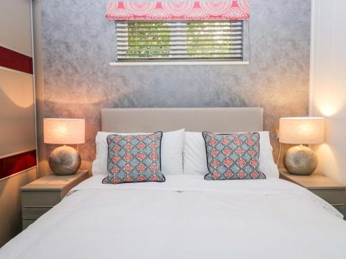 a bedroom with a white bed with two lamps at 5 Waterside Wood in Troutbeck Bridge