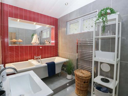 a bathroom with a tub and a sink and red tiles at 5 Waterside Wood in Troutbeck Bridge