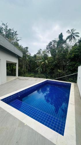 - une piscine avec du carrelage bleu sur le côté d'une maison dans l'établissement Casa com piscina - Costa do Sol, à Bertioga