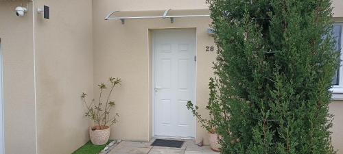 a white door in a building with two plants at Chambre privée in Montaigu-Vendée