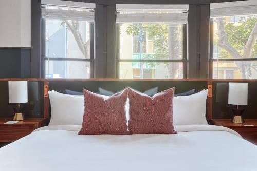 a bedroom with a white bed with pillows and windows at The Davis Downtown San Diego in San Diego
