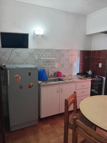 a kitchen with a refrigerator and a sink and a table at Departamentos a 100 mts del mar in San Bernardo