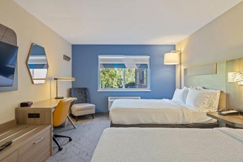 a hotel room with two beds and a desk at Holiday Inn Express Hotel & Suites Torrington by IHG in Torrington