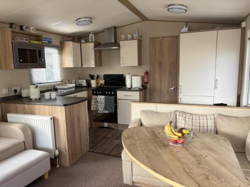 a kitchen with a table with a bowl of fruit on it at Caravan With Decking At Manor Park In Hunstanton, Sleeps 8 Ref 23046B in Hunstanton