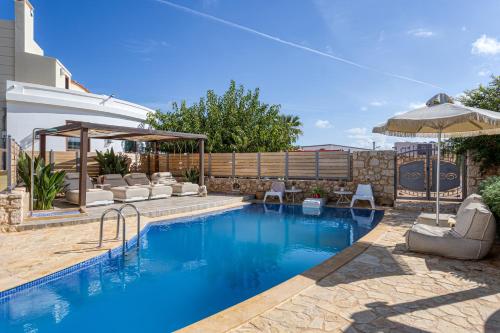 a swimming pool with chairs and an umbrella at Sunshine Villa with Private Pool by Estia in Hersonissos