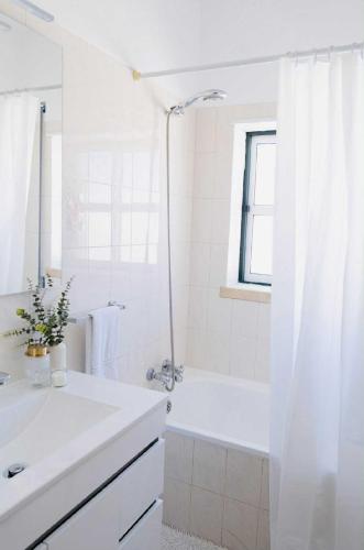 een witte badkamer met een wastafel en een douche bij Maresia Baleal House in Baleal