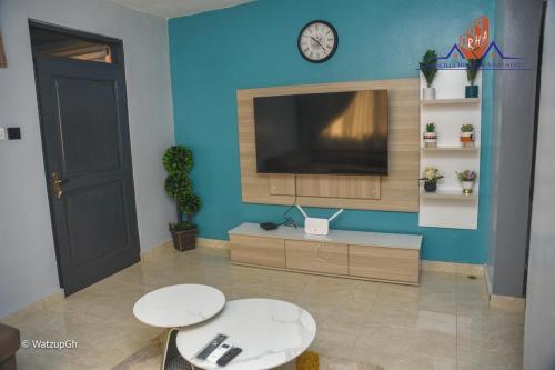 a living room with a flat screen tv on a blue wall at Ranscilla Homes & Apartments in Tema