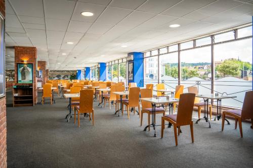 a dining room with tables and chairs and windows at The Grand Burstin Hotel in Folkestone