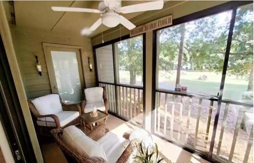 a screened in porch with chairs and a ceiling fan at Coastal Getaway & Golf Retreat Condo in Pawleys Island