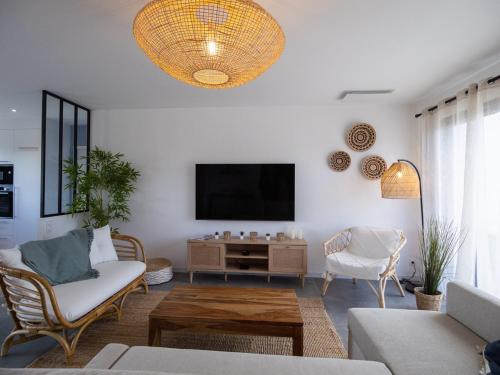 a living room with a couch and a tv at Villa de l'Ile d'Olonne in LʼÎle-dʼOlonne