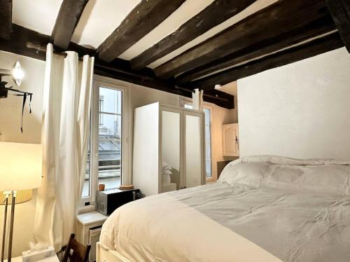 a bedroom with a white bed and a window at Cute Marais Studio near Metro Heart of Paris N4-22 in Paris