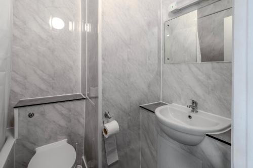 a white bathroom with a sink and a toilet at The Grand Burstin Hotel in Folkestone