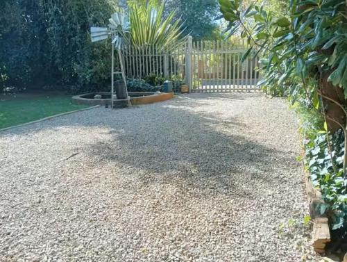a garden with a fence and a gravel driveway at Be Our Guest Near OR Tambo International Airport 2 in Boksburg