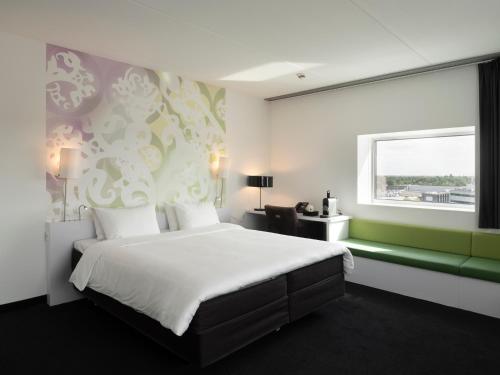 a hotel room with a large bed and a window at Tulip Inn Eindhoven Airport in Eindhoven