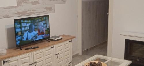 Una sala de estar con un televisor de pantalla plana sobre una cómoda. en Casa Fuente del Caño, en Casarabonela