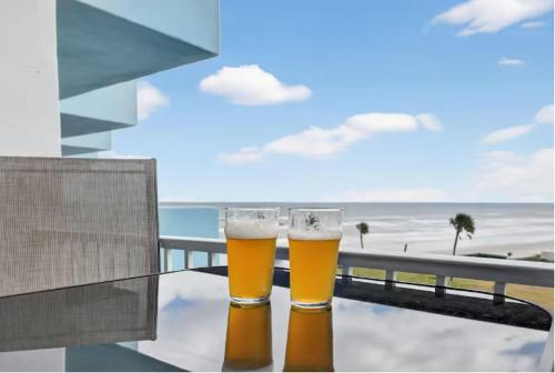 two glasses of beer sitting on a table near the beach at Tiki Time - Daytona Beach Oceanfront Condo! in Daytona Beach