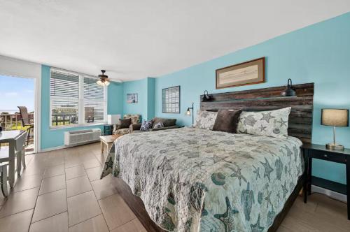 a bedroom with blue walls and a bed and a table at Tiki Time - Daytona Beach Oceanfront Condo! in Daytona Beach