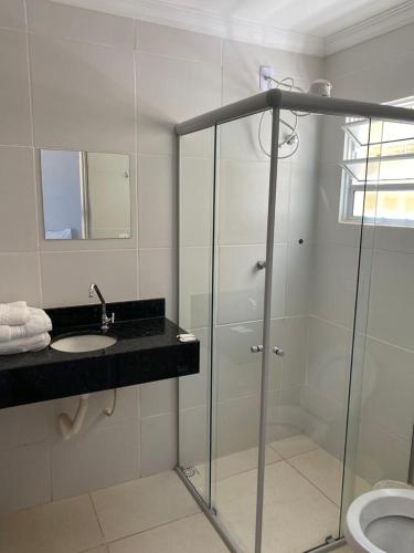a bathroom with a glass shower and a sink at Pousada Trilha do Sol in Pirenópolis