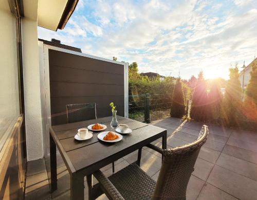 een tafel met twee borden eten op een patio bij Moderne Ferienwohnung mit Sonnenterrasse & Gartenblick - Strandnah und hohem Schlafkomfort in Scharbeutz