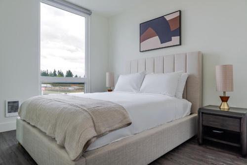 a white bedroom with a large bed and a window at Blueground Lynnwood view nr Lynndale Park SEA-950 in Lynnwood